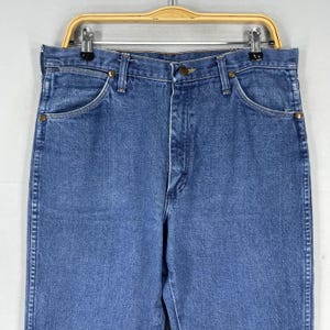 May include: A pair of blue denim jeans with a classic five-pocket style. The jeans have a straight leg and a button fly.