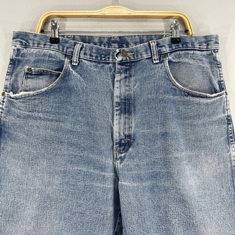 May include: A pair of light blue denim jeans with a button fly and five pockets.