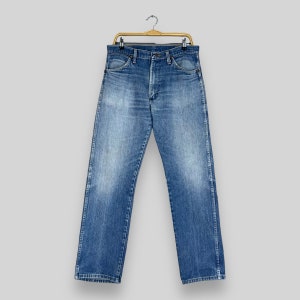 May include: A pair of blue denim jeans hanging on a gold hanger. The jeans have a classic straight leg style and are made of a soft, comfortable fabric.