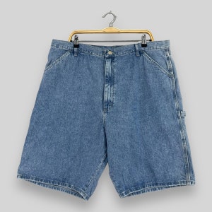 K&ouml;nnte beinhalten: Eine blaue Jeans-Shorts mit einem Zimmermann-Design. Die Shorts haben eine helle Waschung und h&auml;ngen an einem Holzb&uuml;gel.