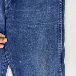 K&ouml;nnte beinhalten: Nahaufnahme des Jeansstoffes einer blauen Jeans. Der Stoff hat einen leicht verblassten Look und eine subtile Textur.