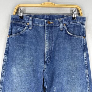 May include: A pair of blue denim jeans with a classic straight leg fit. The jeans have a light wash and are made of a durable cotton blend.