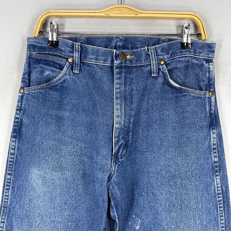 May include: A pair of blue denim jeans with a classic straight leg fit. The jeans have a light wash and are made of a durable cotton blend.