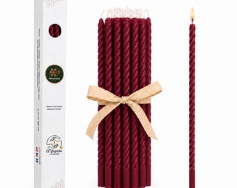 Puede incluir: Un conjunto de velas cónicas de color rojo oscuro con forma de espiral, atadas con una cinta de color tostado claro, junto a una caja rectangular blanca con el texto El Yapımı, Natural Handmade Beeswax Candle y un logo de panal.
