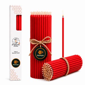 Puede incluir: Paquetes de velas rojas de cera de abejas, algunos atados con hilo. Una vela está encendida, mostrando una llama. Una caja blanca con el texto "El Yapımı Handmade Natural Beeswax Candle" y un logotipo está a la izquierda.