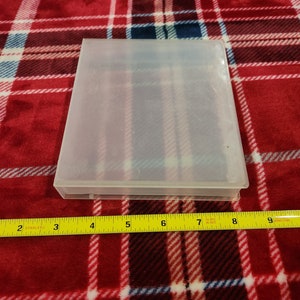 Op de afbeelding: Een transparante plastic opbergdoos met een glad oppervlak. De doos is ongeveer 20 cm lang.