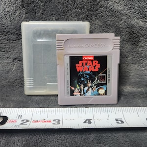 May include: A light grey Nintendo Game Boy Star Wars video game cartridge and its protective case. The cartridge has the text "STAR WARS" and "Nintendo GAME BOY". A Craftsman measuring tape is in the foreground.