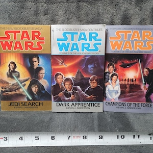 May include: Three Star Wars books from the Jedi Academy Trilogy. The covers feature images of characters and spaceships. Titles include "Jedi Search", "Dark Apprentice", and "Champions of the Force". The books are by Kevin J. Anderson.
