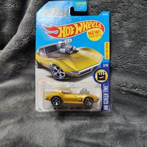 May include: A white ceramic mug with a black handle and the text "But First, Coffee" in a black, bold font. The mug is on a white surface.