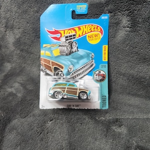 May include: A blue and wood-paneled Hot Wheels toy car labeled "SURF 'N TURF" on a blue and white card. The car has a large engine and chrome wheels. The packaging reads "NEW! FOR 2017".