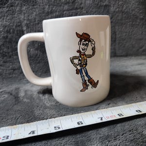 Puede incluir: Una taza de cer&aacute;mica blanca con un asa negra y el texto "But First, Coffee" en negro, en negrita. La taza est&aacute; sobre una superficie blanca.