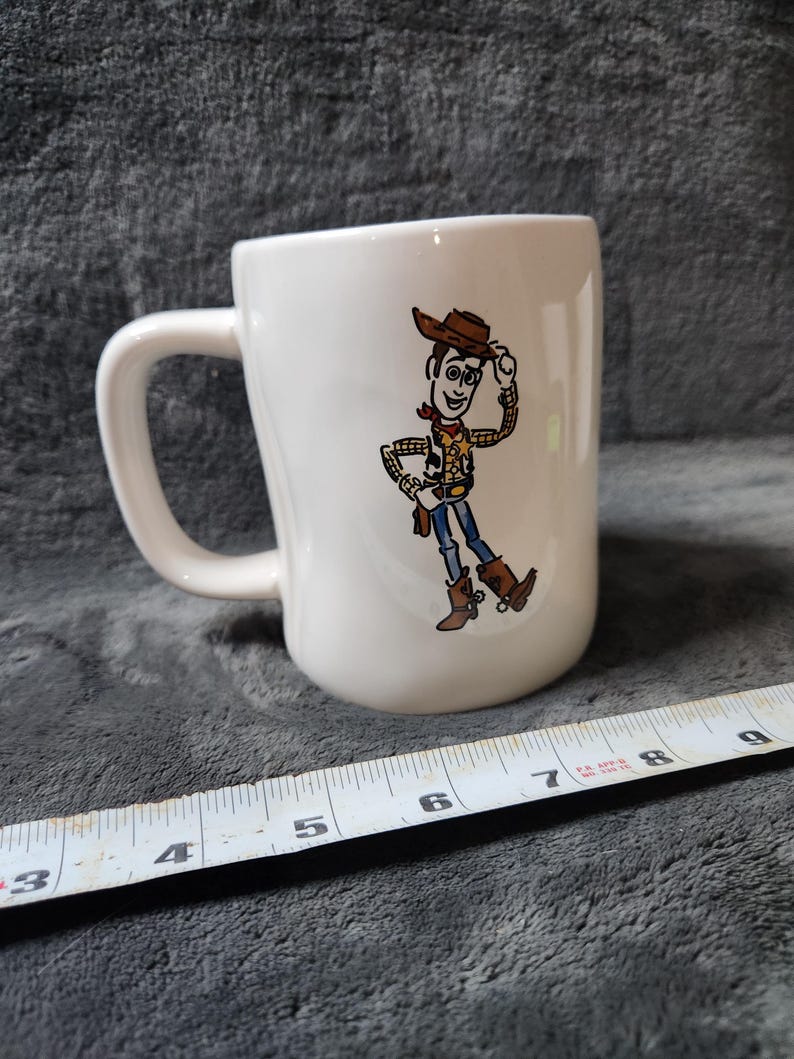 Puede incluir: Una taza de cer&aacute;mica blanca con un asa negra y el texto "But First, Coffee" en negro, en negrita. La taza est&aacute; sobre una superficie blanca.