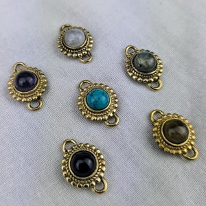 Puede incluir: Seis abalorios de metal dorado con piedras preciosas de diferentes colores. Cada abalorio tiene dos lazos para sujetarlo a un collar o pulsera.