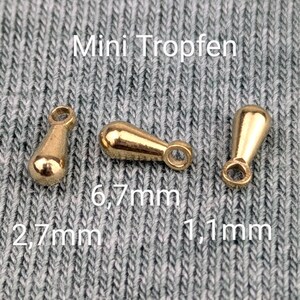 Pode incluir: Tr&ecirc;s pingentes de metal em forma de l&aacute;grima de cor dourada com um la&ccedil;o no topo. Os pingentes medem 2,7 mm, 6,7 mm e 11 mm. O texto "Mini Tropfen" &eacute; vis&iacute;vel acima dos pingentes.
