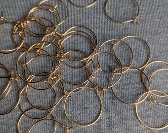 May include: A collection of thin, circular gold-toned metal hoops designed for jewellery making. Each hoop features a simple wire closure mechanism, allowing the ring to open and close securely. The hoops are scattered in a loose, overlapping arrangement.
