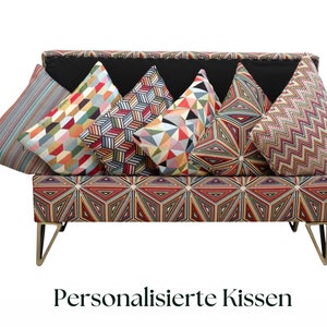 Op de afbeelding: Een kleurrijke gepatroneerde bank met zes kleurrijke gepatroneerde kussens. De bank heeft gouden metalen poten en de tekst "Personalised Cushions" is onder de bank gedrukt.