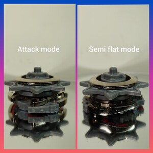 May include: Two gray and silver toy tops are shown in different modes. The left top is labeled "Attack mode" and the right top is labeled "Semi flat mode". The tops have a star-shaped design and a silver ring.