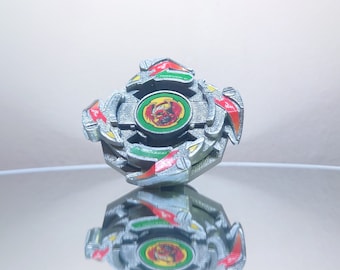 May include: A silver and green Beyblade with red accents. The Beyblade has a red, yellow, and green design on the center piece. The Beyblade is on a reflective surface.