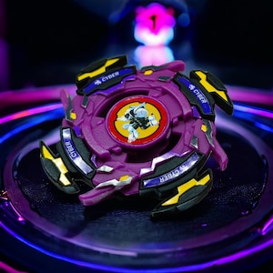 May include: Purple and black Beyblade with yellow accents and the word "CYBER" printed on the sides. The Beyblade has a red and white center with a silver and black design.