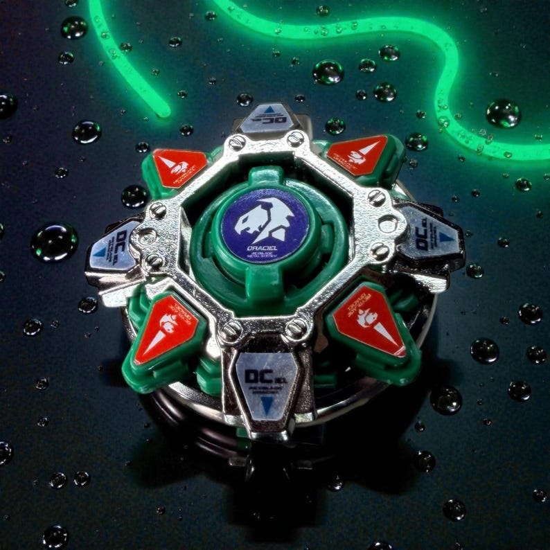 May include: A green and silver toy with red and blue accents. The toy has a central green disc with a white and blue emblem and the word "DRACIEL" printed on it. The toy is surrounded by silver metal and has several red and blue triangular pieces.