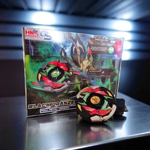 May include: A Black Dranzer toy, a full metal version, is displayed with its packaging. The toy is black, red, green, and yellow. The packaging has the words "Black Dranzer" and "Heavy Metal System" printed on it.