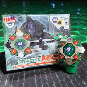 May include: A green and gold toy with red accents, labeled "DRACIEL" and "BENCHBLADE 2028." The packaging features a detailed illustration of a character and the text "HEAVY METAL SYSTEM." The toy has a circular design with a green center.