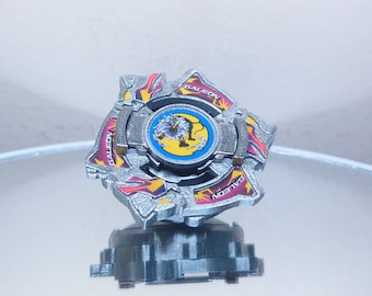 May include: A silver and red Beyblade with a dragon design and the word "Galeon" printed on the side.
