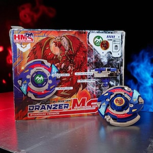 May include: A boxed Dranzer Benchblade 201 toy set. The box features a red and orange illustration of a bird-like creature. The toy is blue, red, and silver with the text "Dranzer" and "Heavy Metal System". A second toy is displayed next to the box.