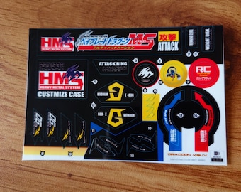 May include: A black and yellow sticker sheet with the text "Heavy Metal System" and "Customize Case". The sheet also includes images of a dragon, a spinning top, and a robot.