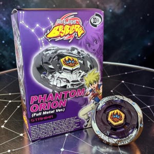 Könnte beinhalten: Ein verpacktes "Metal Fight Beyblade" Spielzeugset mit einem "Phantom Orion" Kreisel. Die Schachtel ist lila mit Charakterillustrationen und Produktdetails. Ein separater, montierter Kreisel ist ebenfalls sichtbar und zeigt ein metallisches Design.