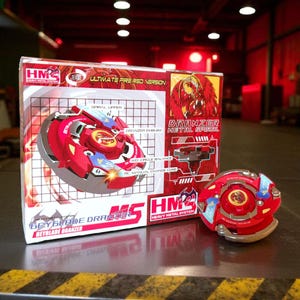 May include: A red and blue Beyblade Dranzer toy with its box. The box reads "Ultimate Fire Red Version" and "Heavy Metal System". The toy is red with blue and yellow accents. The box features a graphic of a red dragon.