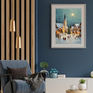 May include: A framed winter landscape painting depicts a snow-covered village with a church and a full moon. The artwork is displayed on a dark blue wall, complemented by a blue armchair, a wooden side table, and gold pendant lights.