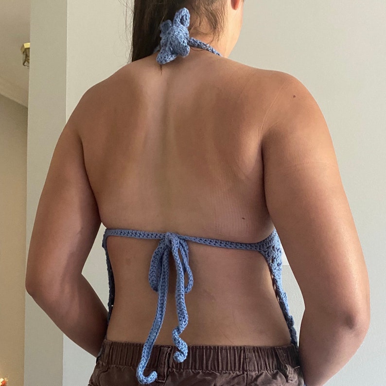 Pu&ograve; includere: Un top halter in crochet blu chiaro con lacci alla schiena. Il top &egrave; realizzato in un materiale morbido e leggero e ha un design delicato e femminile.