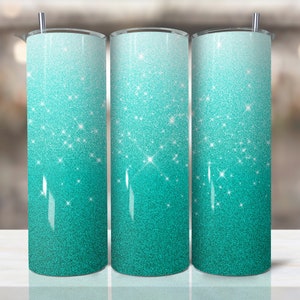 May include: Three stainless steel tumblers with a teal glitter ombre design. The tumblers are lined up in a row on a white surface.