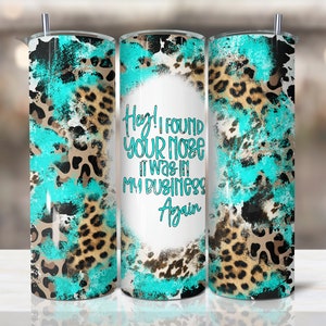 May include: A stainless steel tumbler with a turquoise, brown, and black animal print design. The tumbler has the text "Hey! I found your nose it was in my business again" in turquoise script. The tumbler has a silver straw.