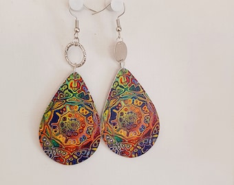 May include: A pair of colorful teardrop earrings. The earrings feature a vibrant, intricate pattern in shades of blue, orange, yellow, and green. The earrings are suspended from silver-colored hooks and decorative rings.
