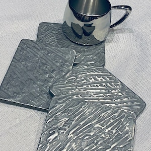 Ein Satz von vier Metalluntersetzern, handgefertigte Metalluntersetzer, silberne zeitgenössische Innendetails, Metalluntersetzer aus Edelstahl.