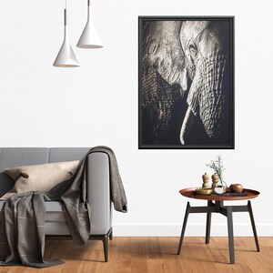 Peut inclure: Une photographie en noir et blanc d'un visage d'&eacute;l&eacute;phant, encadr&eacute;e dans un cadre noir. La trompe de l'&eacute;l&eacute;phant est enroul&eacute;e et ses yeux sont ferm&eacute;s. La photographie est accroch&eacute;e &agrave; un mur blanc au-dessus d'un canap&eacute; gris.