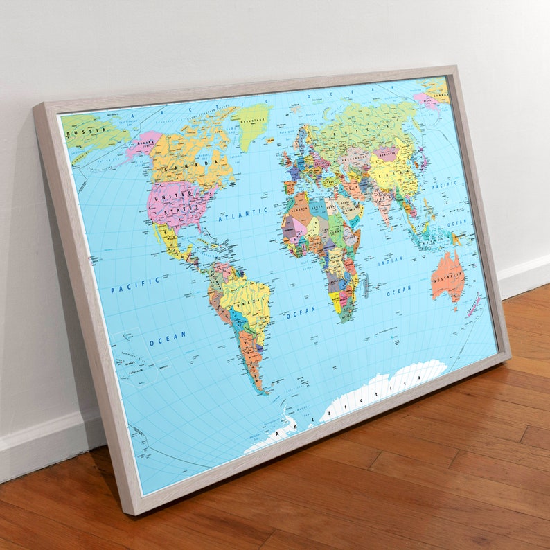 May include: A framed world map with a blue background and colorful borders for each country. The map is in a light wood frame.