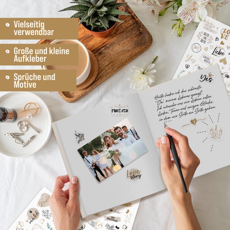 May include: A white scrapbook with gold accents and stickers. The scrapbook is open to reveal a photo of a couple and a handwritten message. The stickers include phrases like "Forever", "Love Story", "Be Mine", and "Yes".