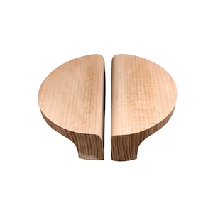 May include: A pair of wooden cabinet door pulls, each shaped like a half-circle. The pulls are made of light-coloured wood with a natural finish.