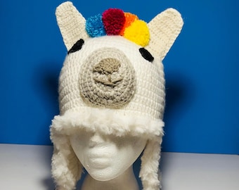 May include: White crocheted llama hat with colorful pom poms on top and a braided cord with tassels.