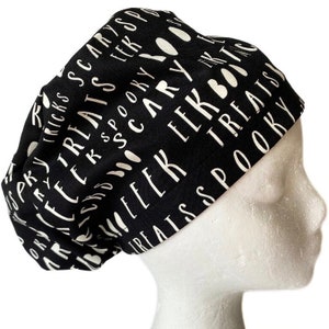 May include: Black scrub hat with a white print of Halloween words like "treats", "spooky", and "boo".