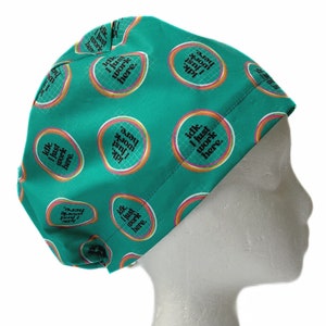 May include: A teal surgical scrub cap with a repeating pattern of circular designs. Each circle contains the text "Idk. I just work here." in a playful font. The cap is designed to cover the head and hair.