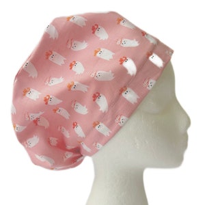 May include: A pink surgical scrub hat with a white ghost pattern. The ghosts are wearing cowboy hats.