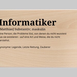 Puede incluir: Un letrero de madera con la palabra alemana "Informatiker" escrita en texto negro. El letrero define la palabra como un sustantivo, que significa "una persona que resuelve problemas de los que no sabías que existían, de una manera que no entiendes". El letrero también enumera sinónimos de la palabra, incluyendo "leyenda", "último recurso" y "mago".