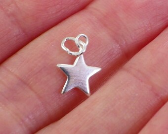 May include: A small, five-pointed star charm made of a shiny, silver-toned metal. The star features a smooth, reflective surface and includes a circular jump ring attached to the top point for easy connection to jewelry chains or other accessories.