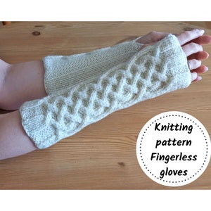 May include: A pair of cream-colored fingerless gloves with a cable knit design. The gloves are made of a soft, textured yarn and have a ribbed cuff. The image includes the text "Knitting pattern Fingerless gloves".