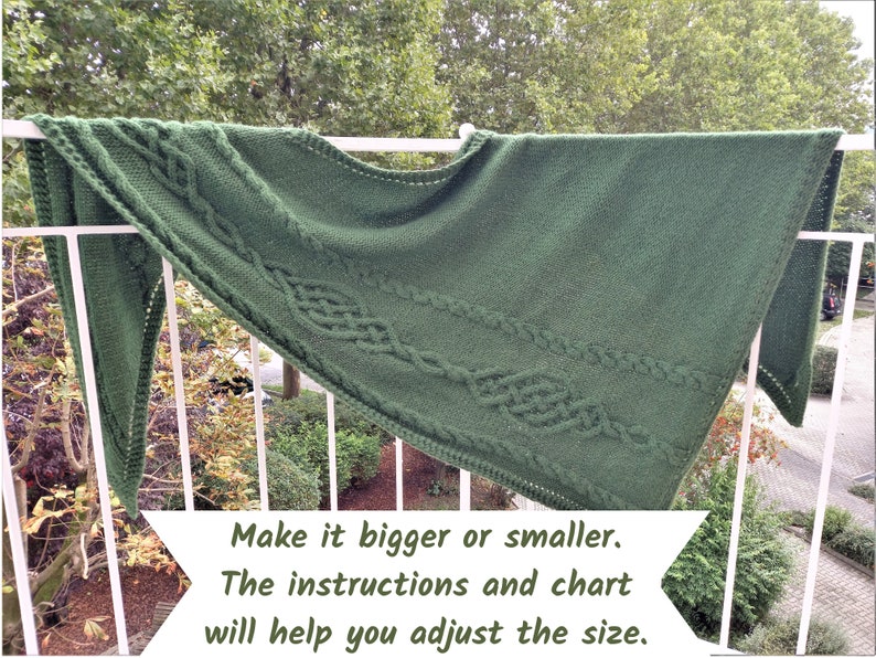 以下が含まれることがあります： ケーブル模様の緑色のニットショール。テキスト「Make it bigger or smaller. The instructions and chart will help you adjust the size.」は白い背景に印刷されています。