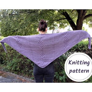 May include: A woman wearing a purple knitted shawl with a cable pattern. The shawl is draped over her shoulders and has a long fringe. The text "Knitting pattern" is visible in the lower right corner of the image.